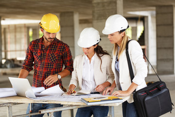 Two female inspectors and architects discuss with head engineer about construction project.