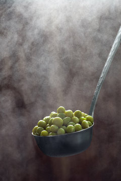 green peas in a saucer with steam on a wooden background