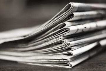 Folded newspapers on the desk. Pile of daily papers with business news, side view, selective focus