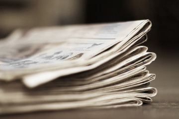Folded newspapers on the desk. Pile of daily papers with business news, side view, selective focus