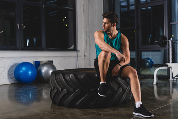 sportsman sitting on tire in sports center