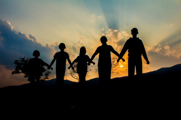 Silhouette group children playing on mountain at sunset time.