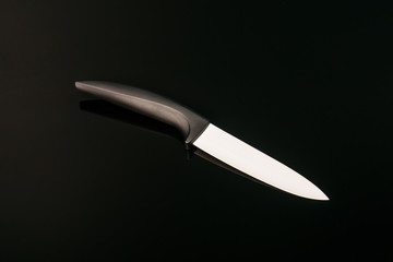 Ceramic knife with black handle isolated on black background