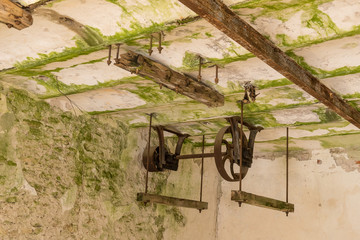 Abandoned watermill. Rusty wheels and green moss covered the old brick wall, natural background