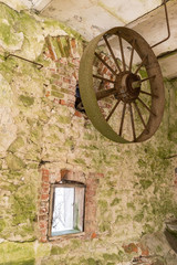 Fototapeta na wymiar Abandoned watermill. Rusty wheels and green moss covered the old brick wall, natural background