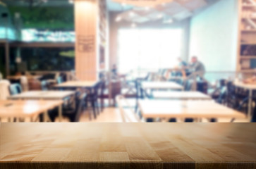 Selected focus empty brown wooden table and Coffee shop or restaurant blur background with bokeh image. for your photomontage or product display.