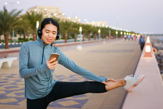 Girl using phone while warming up for outdoor workout - Powered by Adobe