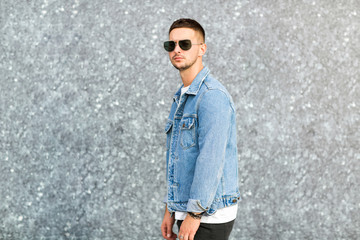 fashion guy standing by a blue marble wall posing in sunglasses