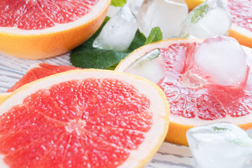 Red grapefruit slices, ice and mint on a white wooden background. The concept of a healthy diet. Detox.