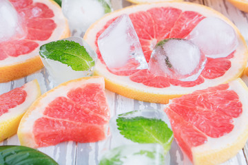 Red grapefruit slices, ice and mint on a white wooden background. The concept of a healthy diet. Detox.