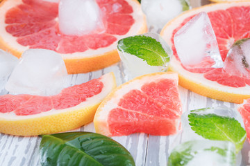Red grapefruit slices, ice and mint on a white wooden background. The concept of a healthy diet. Detox.