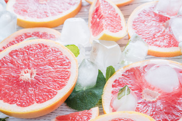 Red grapefruit slices, ice and mint on a white wooden background. The concept of a healthy diet. Detox.