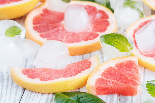 Red grapefruit slices, ice and mint on a white wooden background. The concept of a healthy diet. Detox.