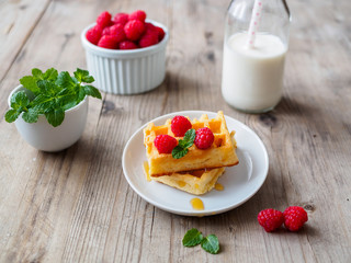 Selbstgebackene Waffeln mit frischen Himbeeren, Honig, Pfefferminze 
