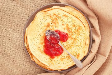 Top view table with pancakes and red raspberry jam on spoon