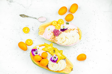 Fresh colourful papaya smoothie bowl on marble background, healthy vegan breakfast concept