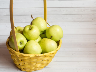 Green ripe apples in a wicker yellow basket