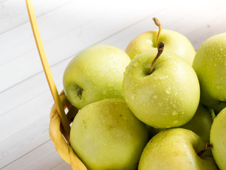 Green ripe apples in a wicker yellow basket