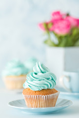 Blue pastel vertical banner with decorated cupcakes, cup of coffe with milk and bouquet of pink roses.
