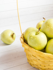 Green ripe apples in a wicker yellow basket