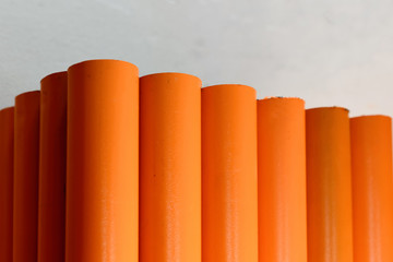 Metal pipes, stand upright. Painted in orange. Concept backgrounds of metal industry.