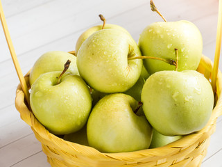Green ripe apples in a wicker yellow basket
