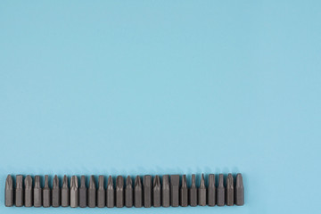 Row of metal bits for screwdriver in form of triangle on blue background with copy space