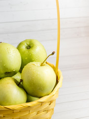 Green ripe apples in a wicker yellow basket