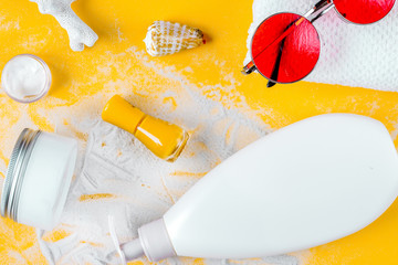 Sun protection cosmetic cream with beach outfit on orange backgr