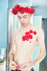 Beautiful aesthetic guy with red flowers on his head and red petals
