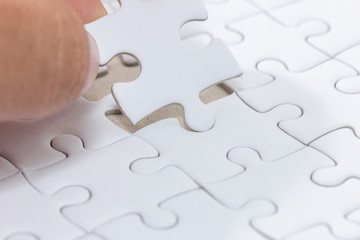 hand holding piece of white jigsaw puzzle