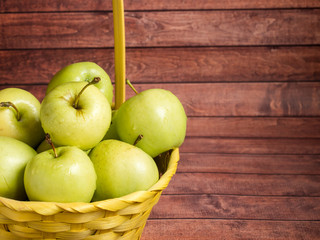 Green ripe apples in a wicker yellow basket