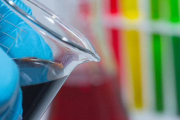 hand holding colorful liquid in Beaker with glove