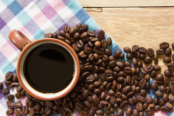 Black coffee in cup and coffee beans on the wooden table