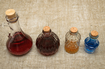 Colorful fluid in decorative bottles on sackcloth background. Medicine.