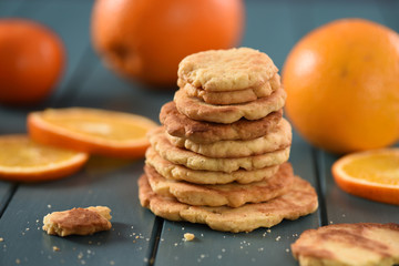 Pile of homemade vegetarian cookies surrounded with orange slices on turquoise background