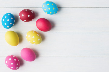 Multicolored Easter eggs over light wooden background.