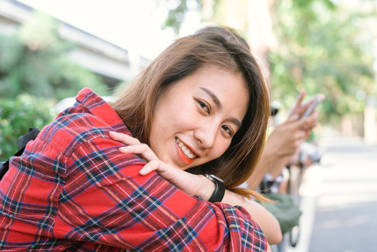 Young Asian women sit and smile along the street enjoying her city lifestyle in a morning of a weekend waiting for out door activity. Young woman and her city lifestyle. lifestyle and outdoor concept