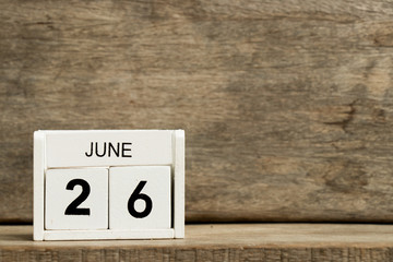 White block calendar present date 26 and month June on wood background