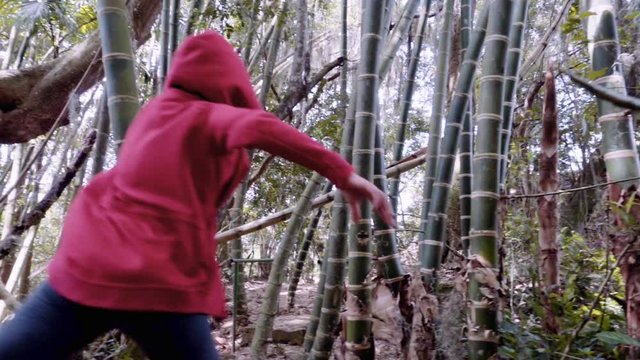 Girl wearing a red hood runs happily through the bamboo jungle in Colombia, Slow motion