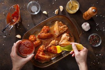 Hands brush baked wings with the bbq souce. - 197516478