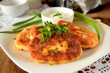 Golden cottage cheese pancakes syrniki and sour cream sauce on a white plate