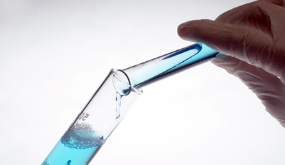 chemical lab, hand pouring liquid from a test tube
