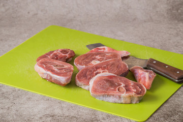 Raw turkey meat (steak) and a knife on a kitchen cutting board on a gray background. 