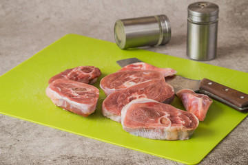 Raw turkey meat (steak) and a knife on a kitchen cutting board on a gray background. 