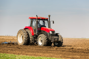 Obraz premium Tractor cultivating field at spring