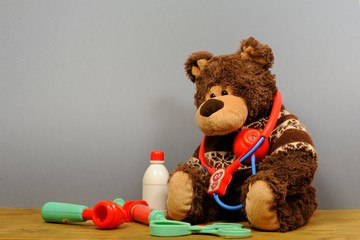 Close up Teddy Bear with Stethoscope Device on on gray background. Person suffering from heart problem. Bear Toy is ill.