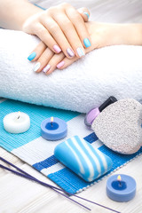 beautiful colored manicure with candle and towel on the white wooden table.