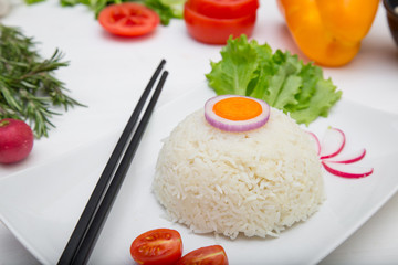 Rice with vegetables on white plate on light background