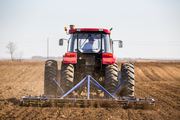 Tractor cultivating field at spring